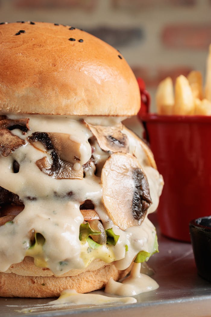 services-img Close-up of a gourmet burger with mushrooms and fries on the side, perfect for food lovers.