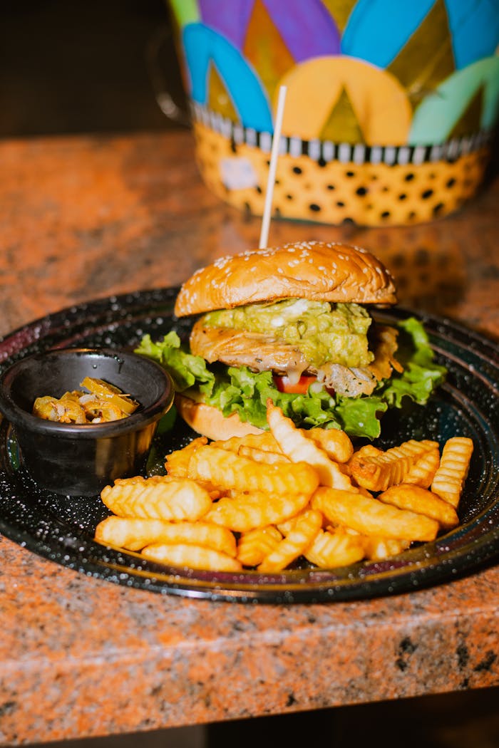 our-services-2 Delicious burger with crinkle-cut fries on a plate, perfect for a fast food indulgence.